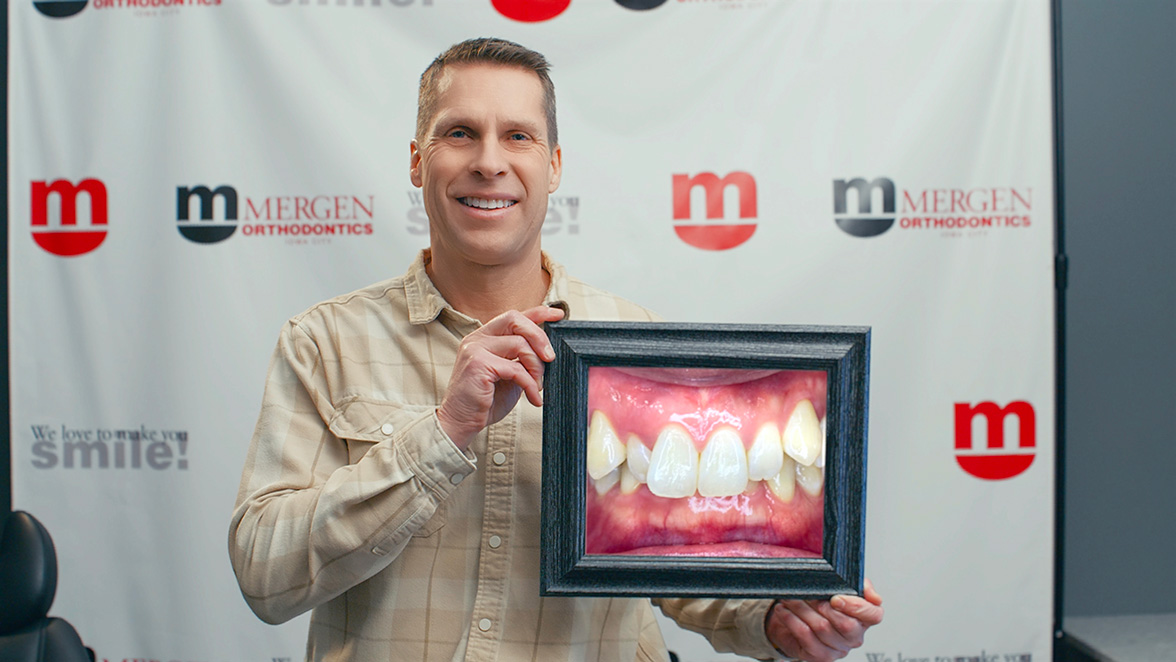 Adult Invisalign patient holding a framed photo of his straightened smile